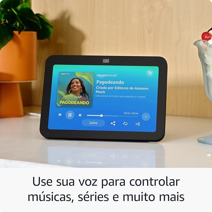 Echo Show exibindo música no Amazon Music em mesa de madeira, mostrando como usar comandos de voz para controlar conteúdos — ideal para quem busca qual dispositivo Echo escolher em 2026.