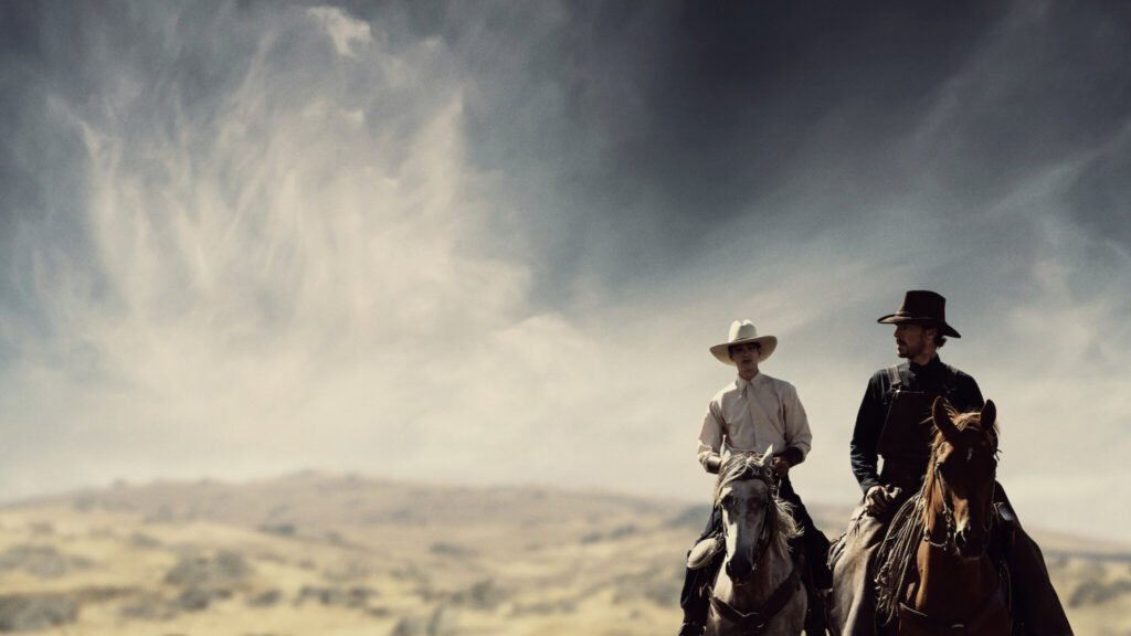 Cena do filme Ataque dos Cães, com dois personagens montados a cavalo em uma paisagem árida do Velho Oeste; um dos melhores filmes originais Netflix, conhecido por sua atmosfera tensa, fotografia ampla e narrativa psicológica premiada.